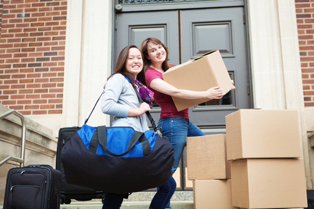 Photo of two women moving into a new rental with boxes and luggage in-hand