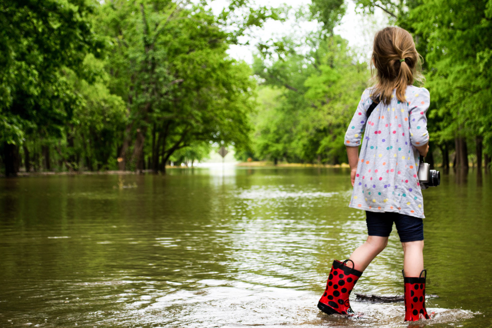 Photo of a girl in boots standing in a flooded road